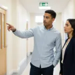 Zak and Sara collaborating in a UK school corridor reviewing connectivity needs.