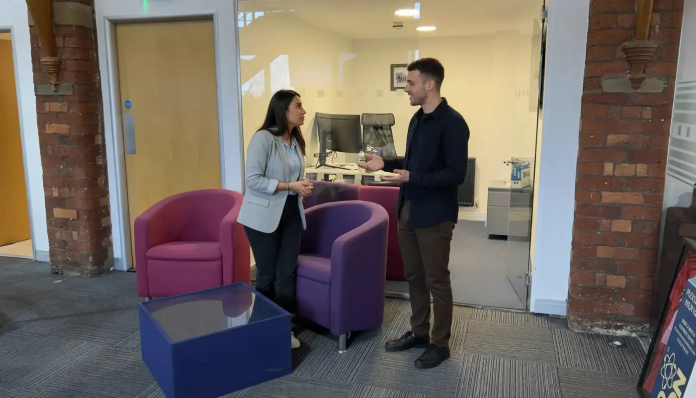 Adam and Sara discussing GitHub hosting in a UK tech workspace, mid-conversation.