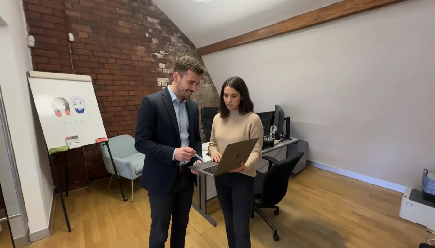 Adam and Sara collaborating in a UK office, discussing local SEO work in a natural mid‑conversation moment.