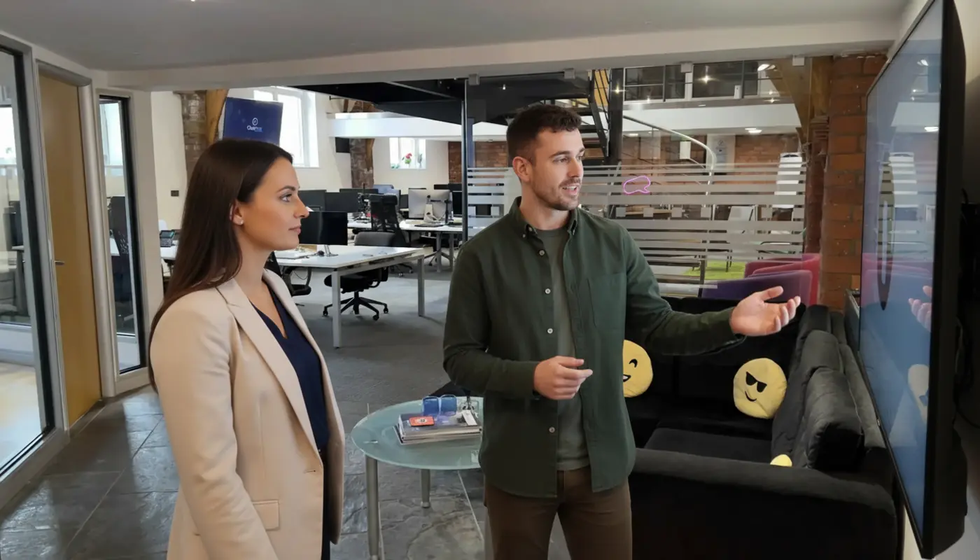 Jessica and Adam collaborating in a UK creative studio, discussing logo design concepts.