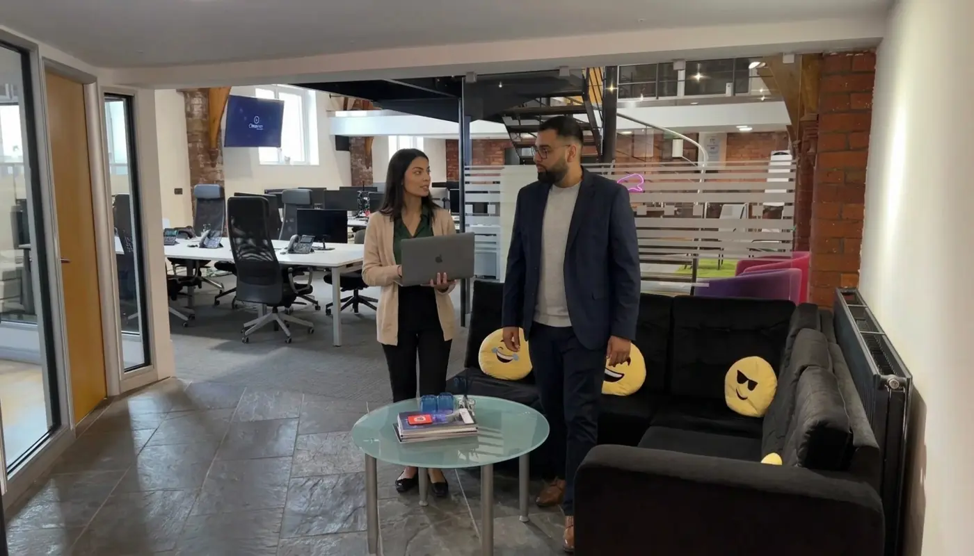 Two colleagues walk through a UK office discussing improvements to a business website.