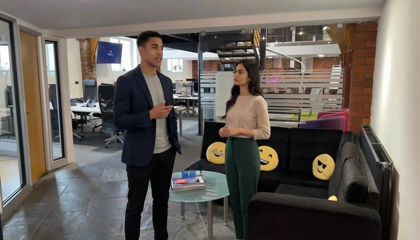 Zak and Jessica discussing branding inside a UK office, captured mid‑discussion.