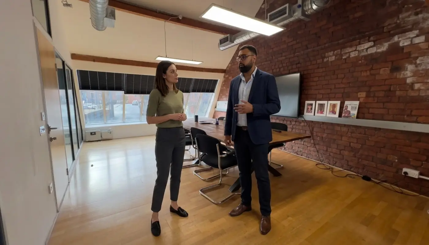 Two professionals discuss workflow automation in a modern office while reviewing a shared area during work.