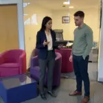 Two colleagues in a UK office review an ecommerce customer journey during an online sales planning discussion.