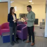 Two colleagues discuss CRM workflow notes in a UK office during a focused planning session.