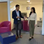 Two colleagues discuss Office 365 setup while walking through a UK office.