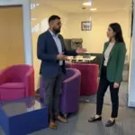 Two colleagues discuss AI workflow improvements in a UK office during a practical business review.
