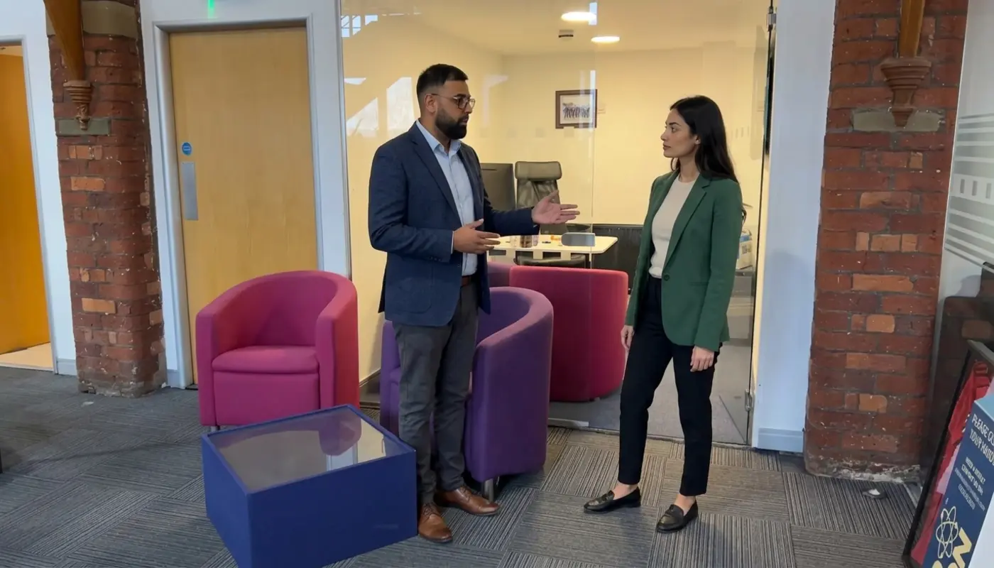 Two colleagues discuss AI workflow improvements in a UK office during a practical business review.