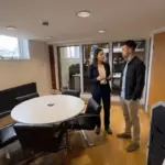 Two colleagues discuss paid social budget planning in a UK office during a professional conversation.