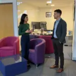 Two professionals discuss website project scope and build costs in a UK office setting.
