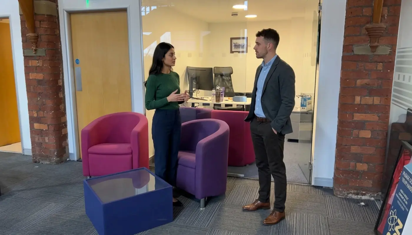Two professionals discuss website project scope and build costs in a UK office setting.