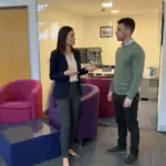 Two colleagues discuss WordPress SEO keyword placement in a modern office setting.