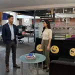 Two colleagues discuss IT support needs in a UK office while assessing a shared workspace.