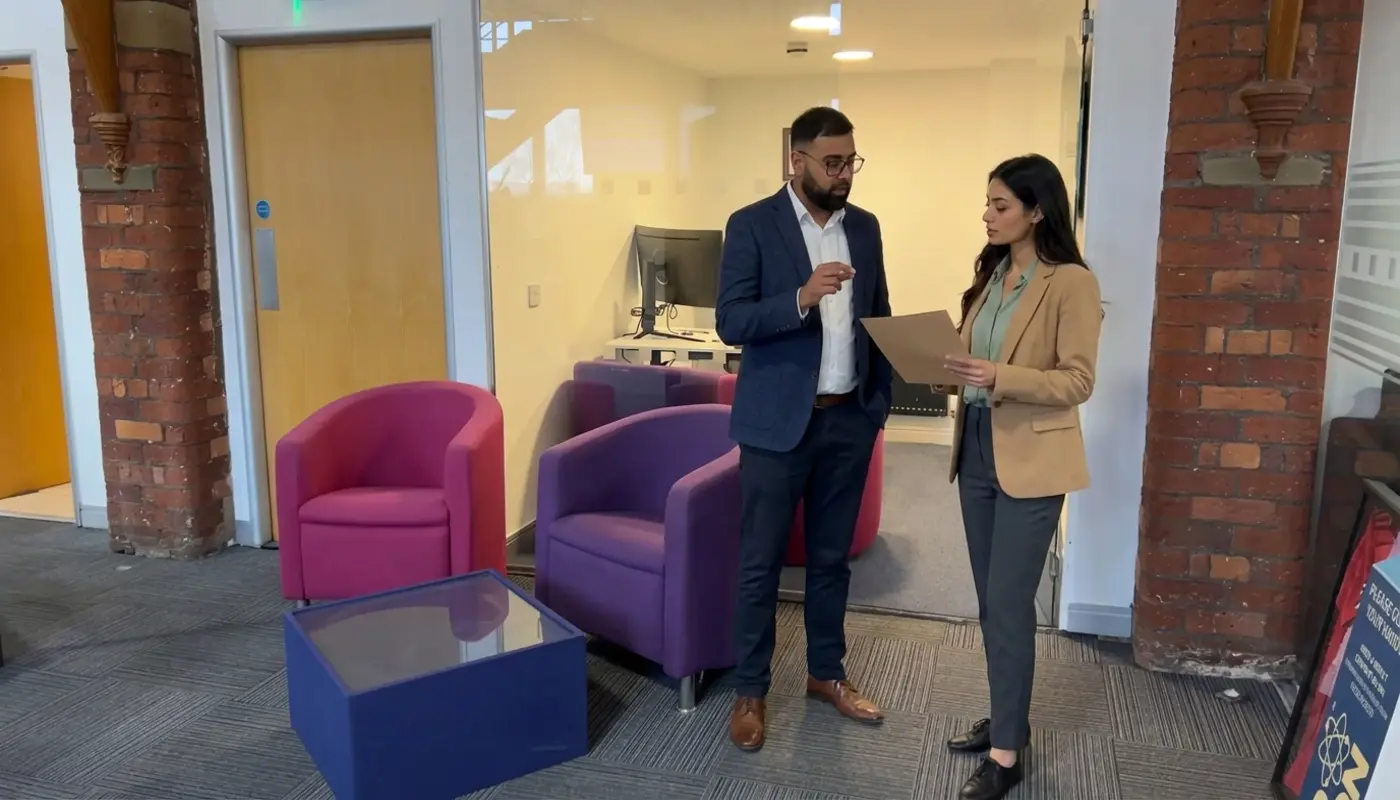 Two colleagues discuss agency selection in a UK office while reviewing a plain brief.