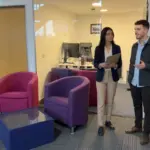Two professionals discuss IT support needs during a walkthrough in a UK office setting.