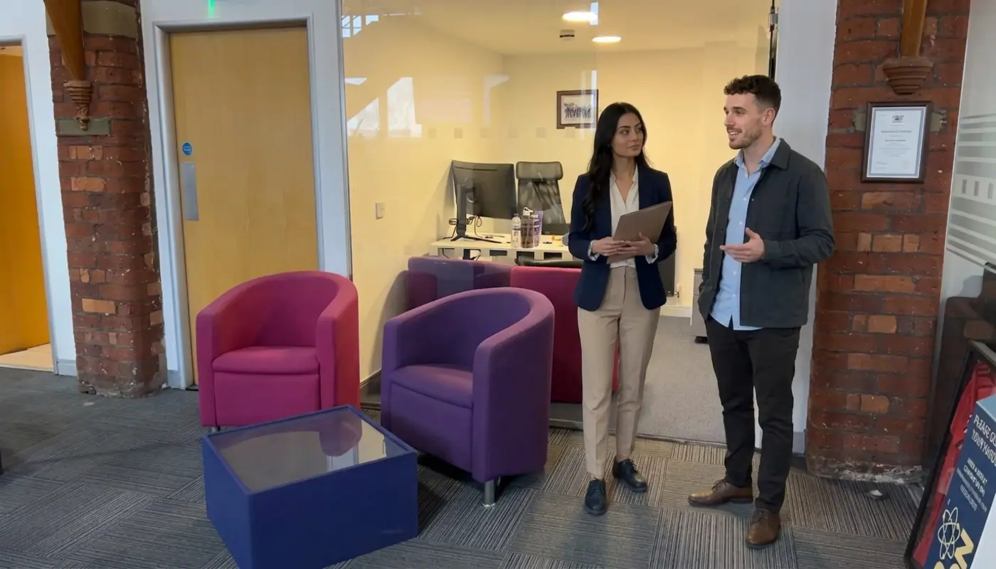 Two professionals discuss IT support needs during a walkthrough in a UK office setting.