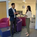 Two colleagues discuss a social media content plan in an office during a focused planning conversation.