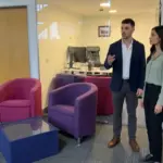 Two colleagues discuss brand positioning in an office while reviewing where a logo would work in the space.