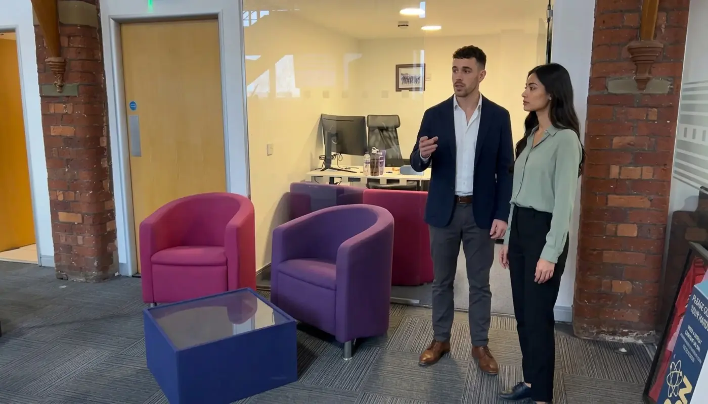 Two colleagues discuss brand positioning in an office while reviewing where a logo would work in the space.