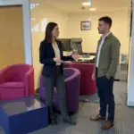 Two colleagues in an office discuss where digital signage would be most visible for staff and visitors.