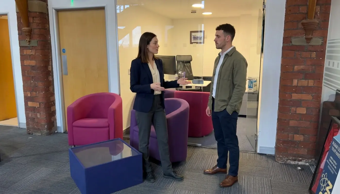 Two colleagues in an office discuss where digital signage would be most visible for staff and visitors.