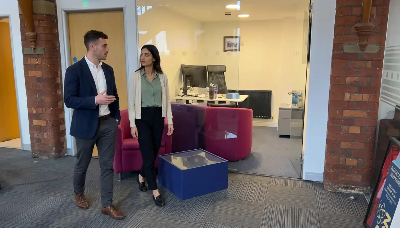 Two colleagues discuss SEO planning in a UK office while moving through a shared workspace.