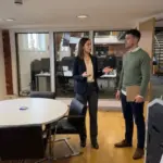 Two colleagues discuss logo consistency in an office during a visual identity walkthrough.