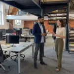 Two colleagues discuss generative search strategy while standing in a modern office setting.