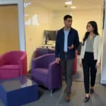 Two colleagues walk through an office discussing IT support processes for smoother team workflows.