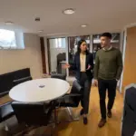 Two professionals discuss connected CRM workflows while walking through a modern office.