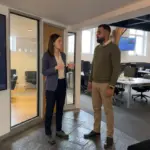 Two colleagues discuss a user journey in an office while reviewing website design decisions.