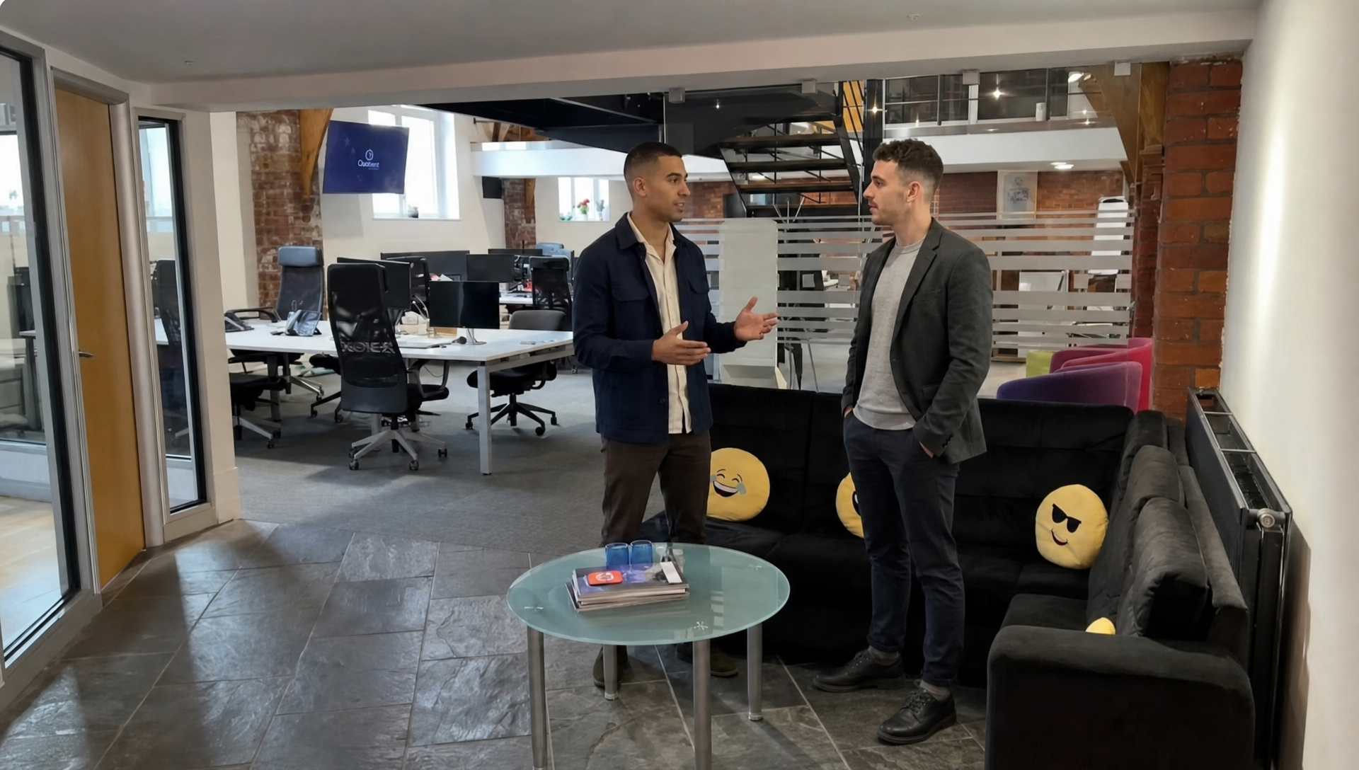 Two colleagues discuss Shopify SEO planning in a UK office while standing in an open workspace.