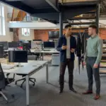 Two colleagues discuss call handling workflows in a UK office during an AI voice agent planning session.