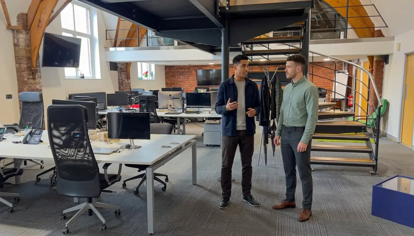 Two colleagues discuss call handling workflows in a UK office during an AI voice agent planning session.