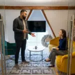 Two colleagues discuss Instagram content strategy in a small office seating area.