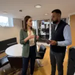 Two colleagues discuss ecommerce SEO priorities in a UK office while reviewing an unreadable tablet.