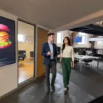 Two professionals walk through an office discussing small business IT support and device management.
