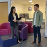 Two colleagues discuss a user journey in a UK office during a UX planning conversation.